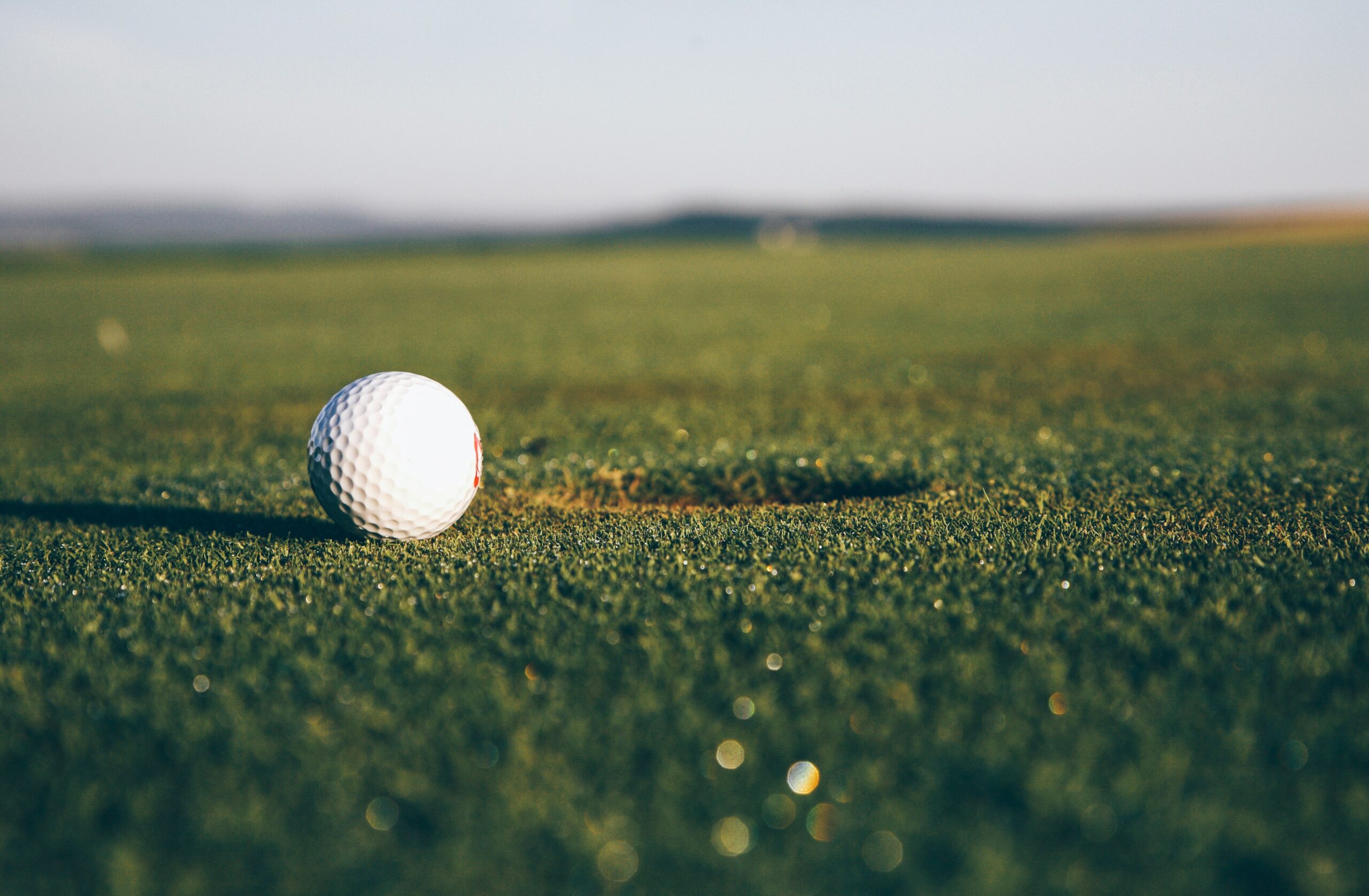 A golf ball beside the hole at golden hour